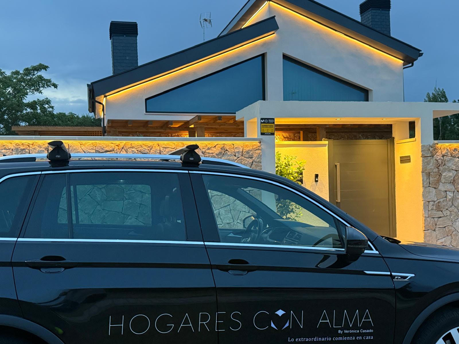 Vivienda de obra nueva iluminada al anochecer con el vehículo de Hogares con Alma en primer plano